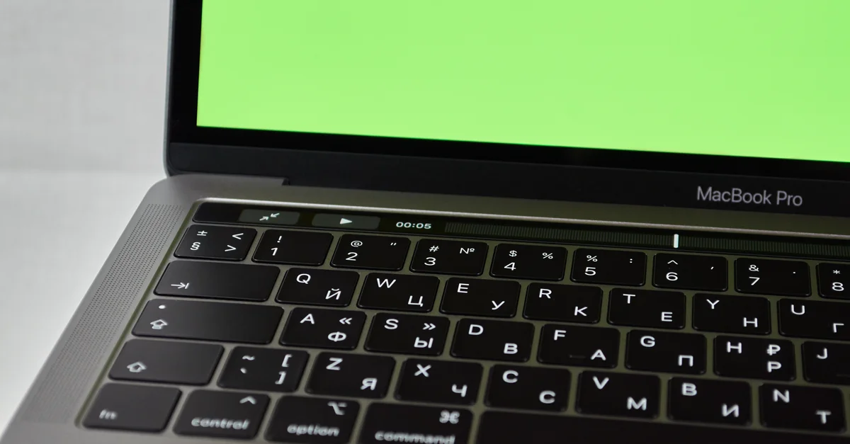 MacBook Pro avec clavier russe et écran vert. Dispositif électronique moderne.