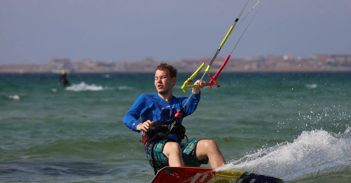 Prise de vue dynamique d'un homme faisant du kitesurf dans l'océan, capturant un mouvement palpitant et des éclaboussures.