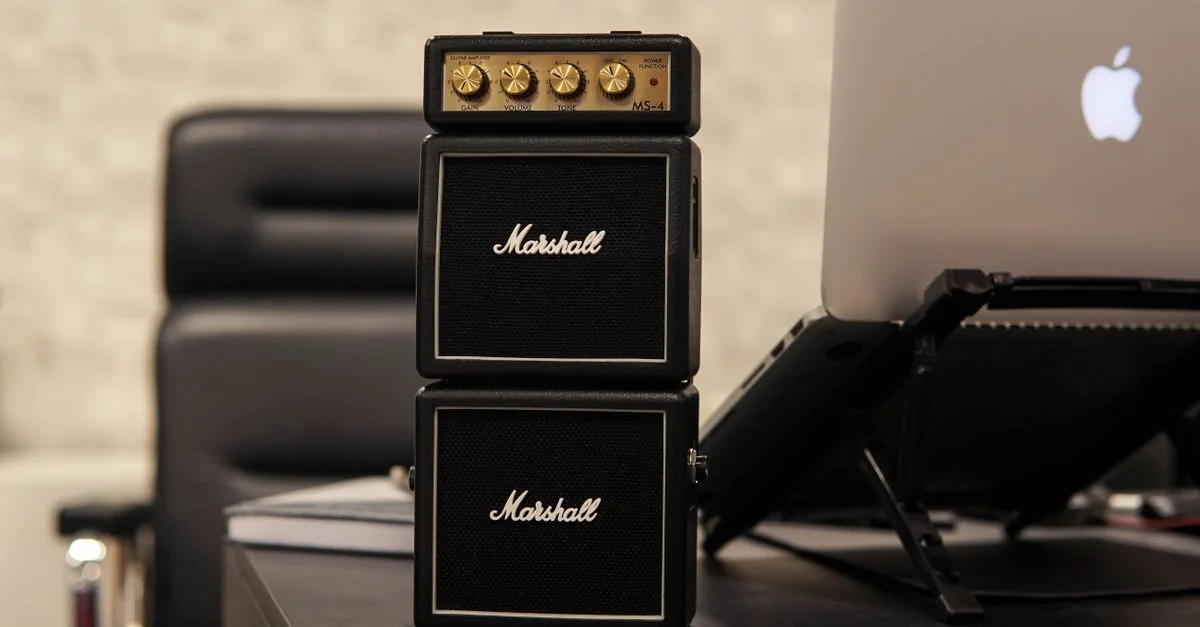 Petit amplificateur Marshall à côté d'un ordinateur portable sur un bureau dans un environnement de bureau moderne.