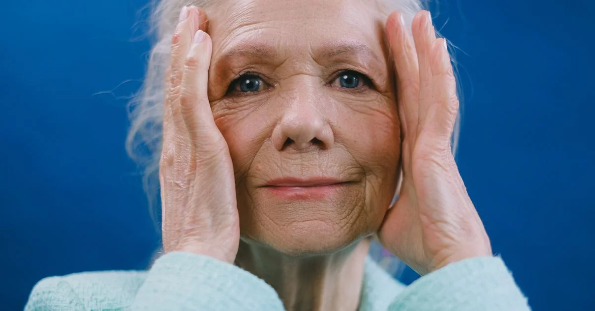 Portrait rapproché d'une femme âgée tenant son visage, exprimant de l'émotion.