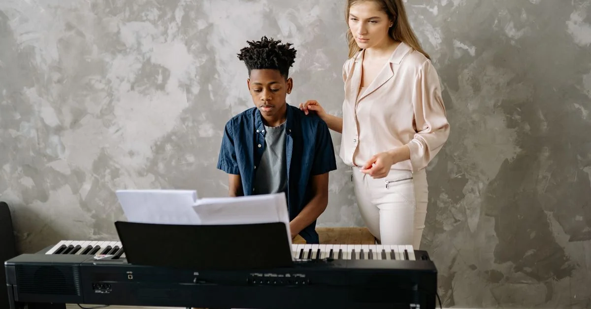 Un garçon apprend le piano d'un professeur dans un cadre domestique.